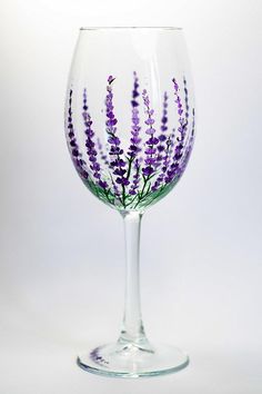 a wine glass with purple flowers painted on the bottom and inside, in front of a white background