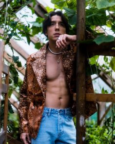 a shirtless man leaning against a wooden pole in the middle of a garden area