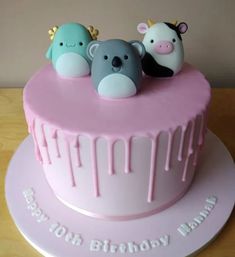 a birthday cake with three little animals on top and driping from the icing