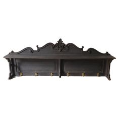 an ornate wooden shelf with brass handles and hooks on the bottom, against a white background