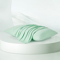 a white round bed with green pillows and sheets on it's headrests