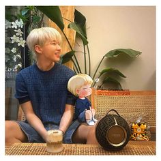 a young man holding a doll sitting next to a woman on a chair with a handbag