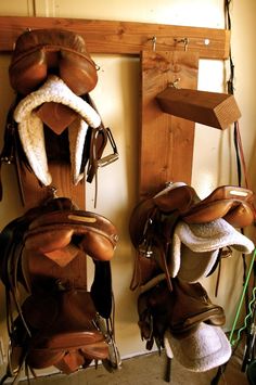 several different types of saddles hanging on a wall