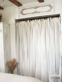 a white bed sitting under a window covered in curtains