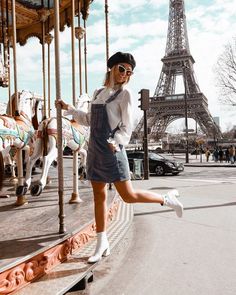 a woman standing in front of the eiffel tower with her legs spread out