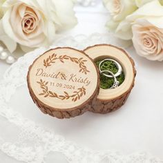 two wedding rings are in a ring box on a lace doily next to flowers