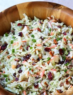 a wooden bowl filled with coleslaw and cranberries