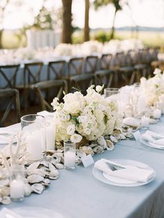 the table is set with white flowers and candles for an elegant wedding reception in southern california