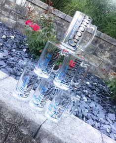 four glasses are stacked on top of each other in front of some plants and flowers