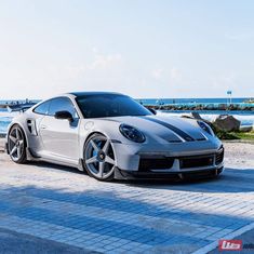 a white sports car parked next to the ocean