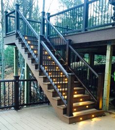 the stairs are lit up with lights in front of a decked area and trees