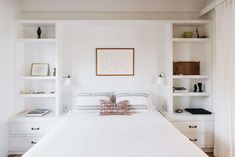 a white bed sitting in a bedroom next to shelves