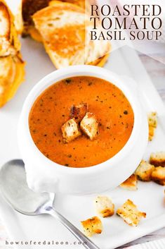 a white plate topped with a bowl of soup and croutons