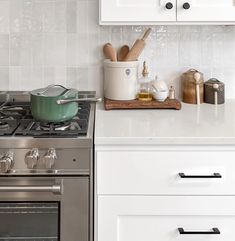 a stove top oven sitting inside of a kitchen next to a wooden cutting board with utensils on it