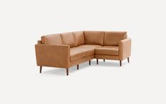 a tan leather sectional sofa with footstool and ottoman in front of a white background