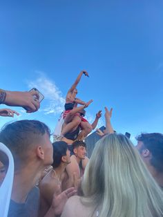 a group of people standing around each other with their arms in the air and one person jumping up into the air