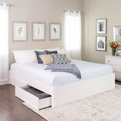 a bedroom with white furniture and pictures on the wall