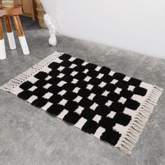 a black and white rug sitting on top of a floor next to a wooden table