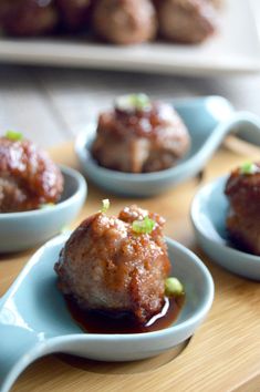 small blue dishes filled with meatballs on top of a wooden table next to other food items