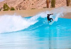 a man riding a wave on top of a surfboard in the ocean next to palm trees