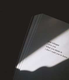 an open book sitting on top of a table next to a shadow cast by a person's hand