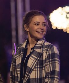 a young woman smiles while standing in front of a stage with lights on the background