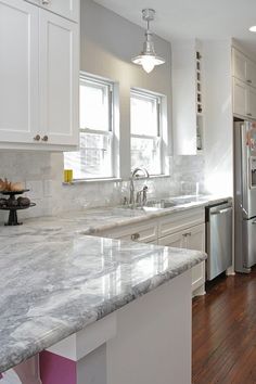 a kitchen with marble counter tops and stainless steel refrigerator freezer next to an island