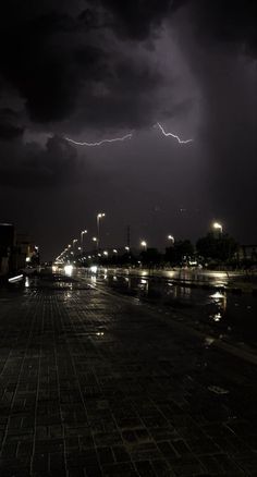 a lightning bolt is seen over a city street at night with lights reflecting in the water