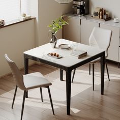 a dining table with two chairs and a plate on it, in front of a window