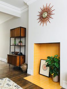 a living room with a fire place next to a book shelf and a potted plant