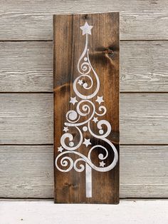 a wooden sign with a christmas tree painted on it's side and white swirls in the shape of a star