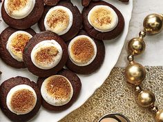 chocolate cookies and marshmallows on a white plate next to gold ornaments, with a glass of milk