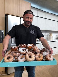 a man holding a tray full of doughnuts