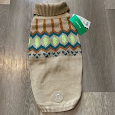 a dog sweater with a tag attached to it's side on a wooden floor