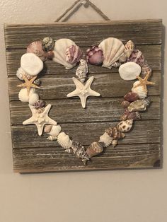 a heart made out of seashells hangs on a wall