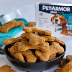 a bowl full of dog biscuits next to a box of petarmor milk and some dogs treats