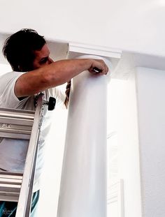 a man that is standing on a ladder with his hand on the edge of a window