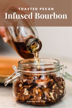 someone pouring caramel syrup into a glass jar filled with cooked pecans and nuts