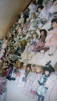 many dolls are lined up on the wall and one is laying down next to another