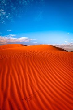 an orange sand dune in the desert under a blue sky