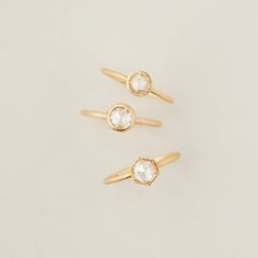 three gold rings with small white stones on each one, all in different shapes and sizes