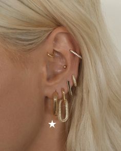 a woman with blonde hair wearing three different ear piercings and one has a star on it