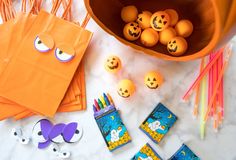 an assortment of halloween crafts and decorations on a marble counter top with orange paper bags