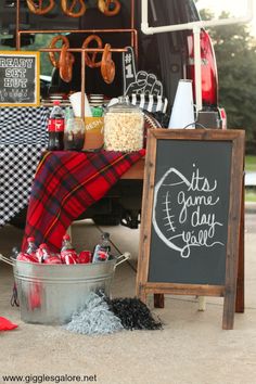 the back of a van with food and drinks on display next to a chalkboard sign