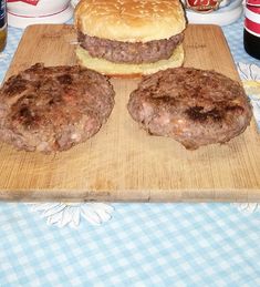 two hamburgers sitting on top of a wooden cutting board