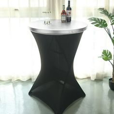 a black table with a bottle of wine on it next to a potted plant