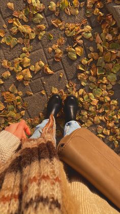 a person standing in front of leaves on the ground with their feet propped up against each other