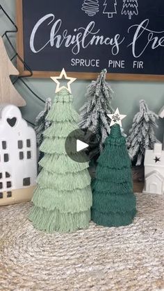 three small christmas trees sitting on top of a table next to a chalkboard sign