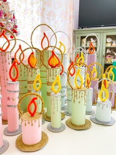 a table topped with lots of different colored candles and decorated christmas trees on top of each other