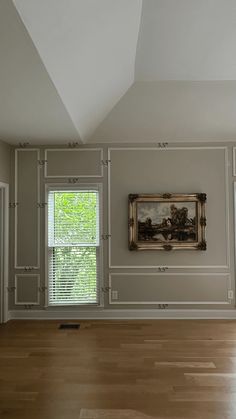 an empty room with two windows and a painting hanging on the wall in front of it